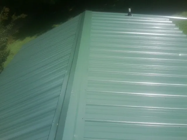 New green metal panels meeting at the ridge of a roof — Flat Roof Repair work by our crew in Eagle