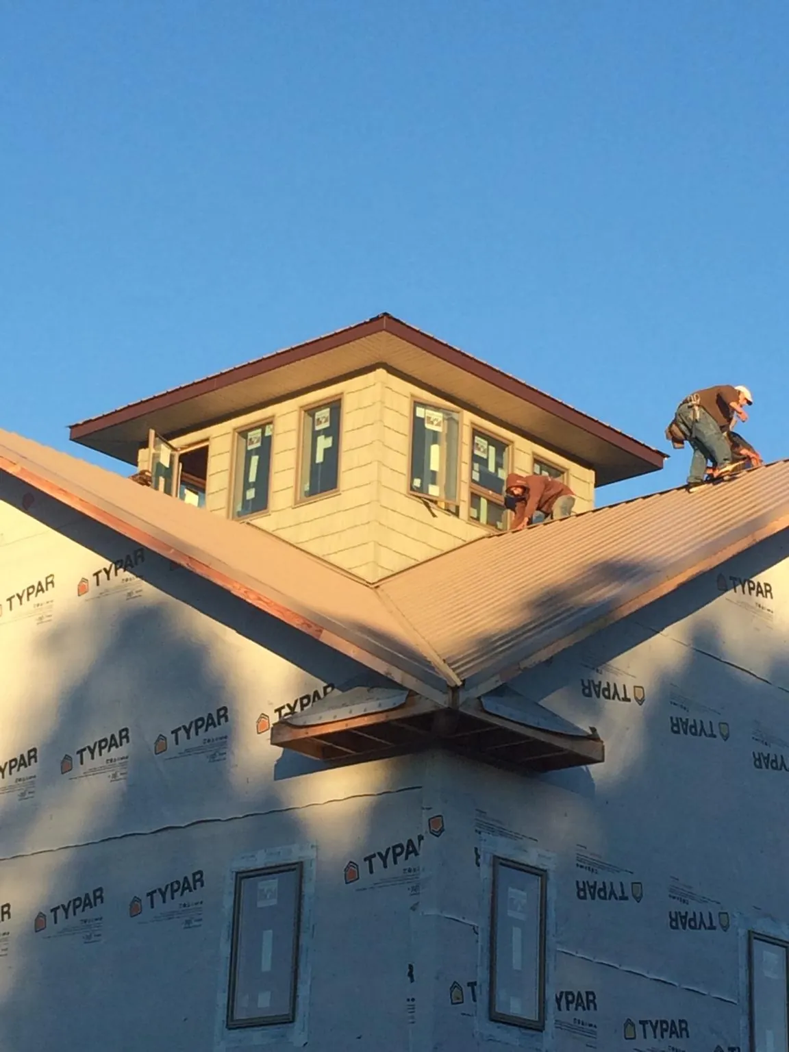Roofers working around a rooftop cupola on a new metal roof at sunset — Roof Waterproofing in Eagle by Roofing Brothers